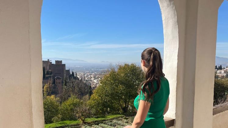 female student standing outside looking at a nice view of the sky